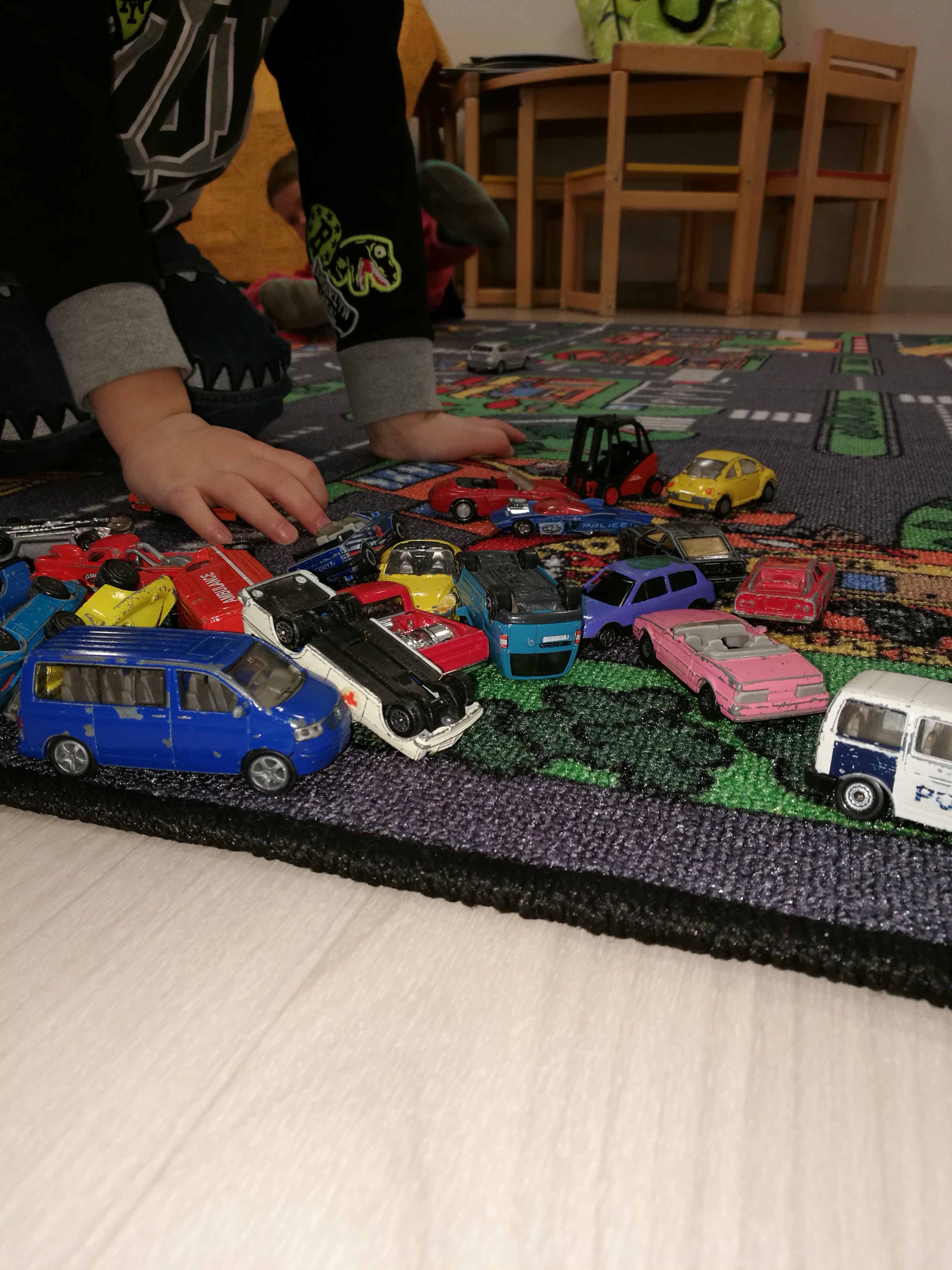 Miniperhekerho pikkuautoja ja lapsen kädet
